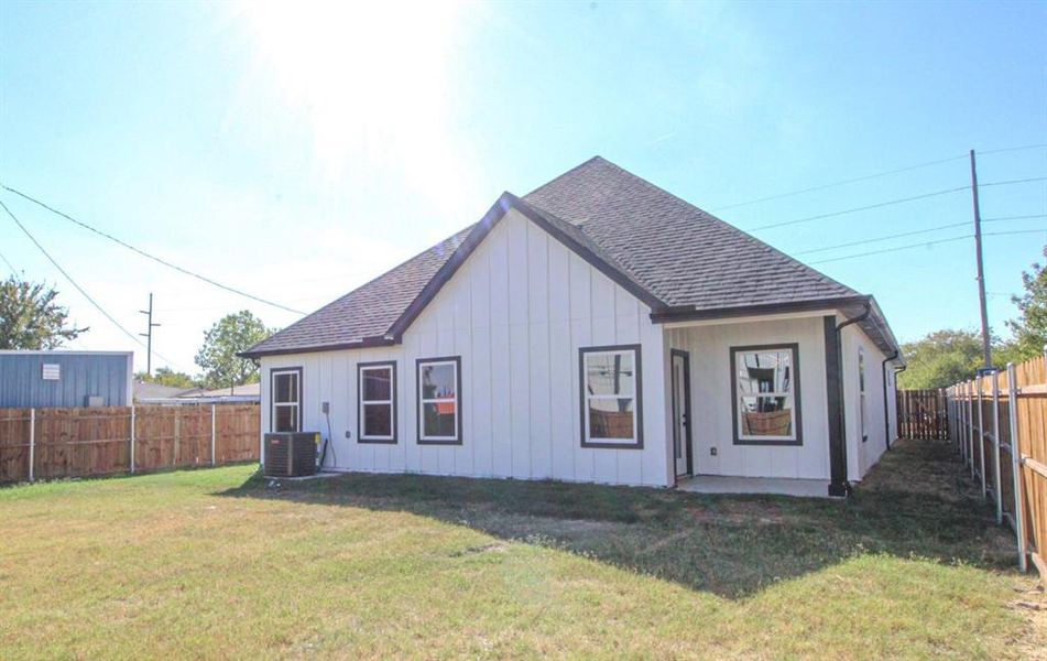 Rear view of property featuring a fenced backyard, a shingled roof, a patio, and board and batten siding Rear view of property featuring a fenced backyard, a shingled roof, a patio, and board and batten siding