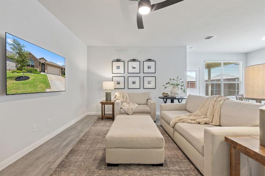 Living area with plenty of natural light, ceiling fan, wood finished floors, and baseboards Living area with plenty of natural light, ceiling fan, wood finished floors, and baseboards