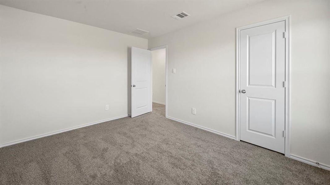 Neutral tone wall paint, gray carpeting, white baseboards, and two-panel interior doors with chrome hardware