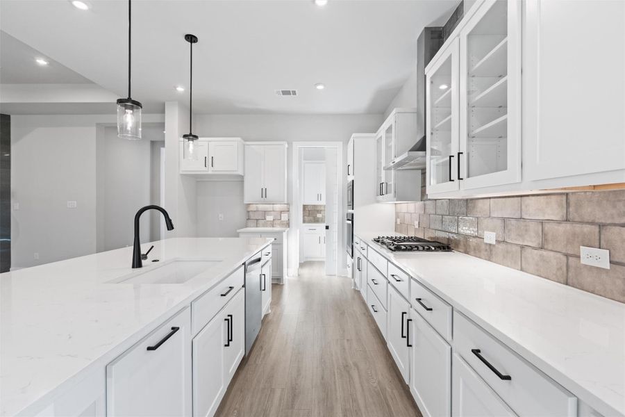 Kitchen featuring glass insert cabinets, pendant lighting, white cabinetry, light stone counters, and light wood finished floors