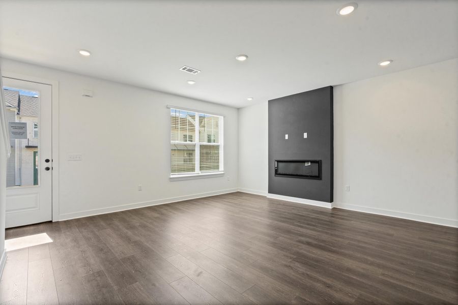 Recessed lighting, wood-finish flooring, white walls, black accent wall, and built-in linear fireplace Recessed lighting, wood-finish flooring, white walls, black accent wall, and built-in linear fireplace