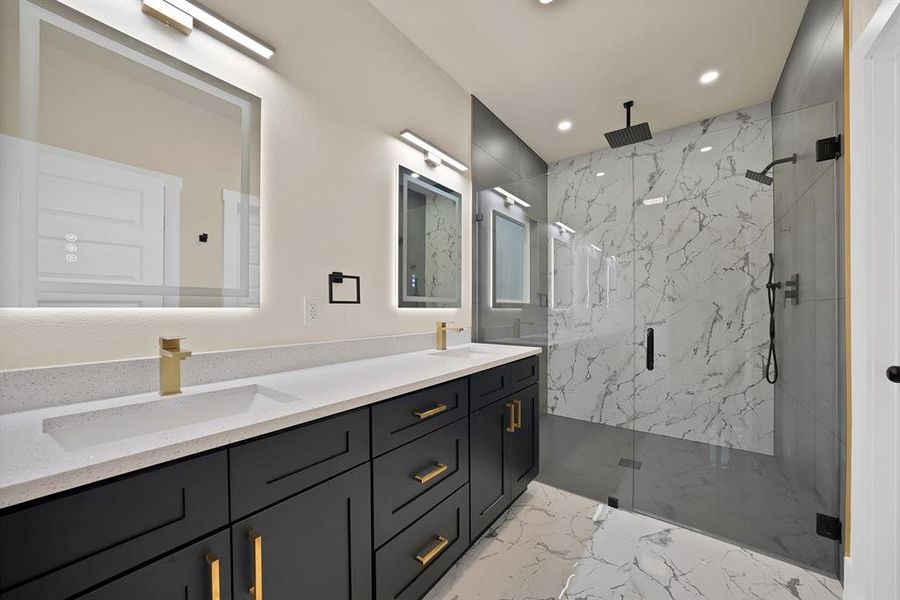 Bathroom with a marble finish shower, double vanity, light marble finish flooring, and recessed lighting