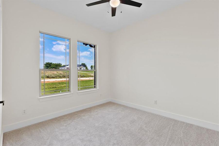Carpeted spare room featuring a ceiling fan and baseboards Carpeted spare room featuring a ceiling fan and baseboards