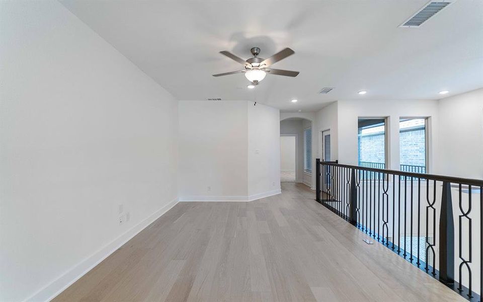 Spacious interior landing featuring light wood-finish flooring, white walls, and a contemporary ceiling fan