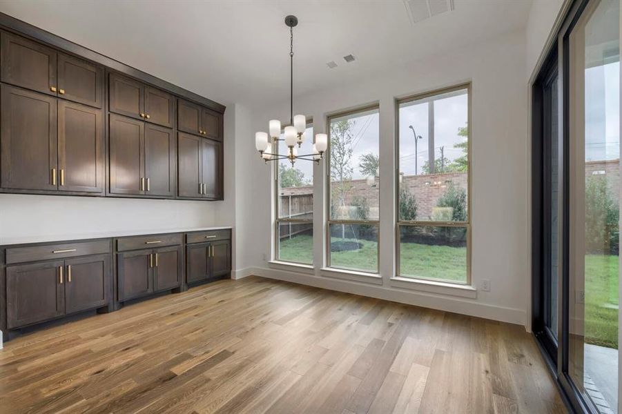 The room features hardwood floors, extensive built-in cabinetry with gold-toned hardware, and a modern chandelier