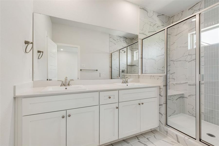 Bathroom featuring a shower with door, tile patterned flooring, and dual bowl vanity