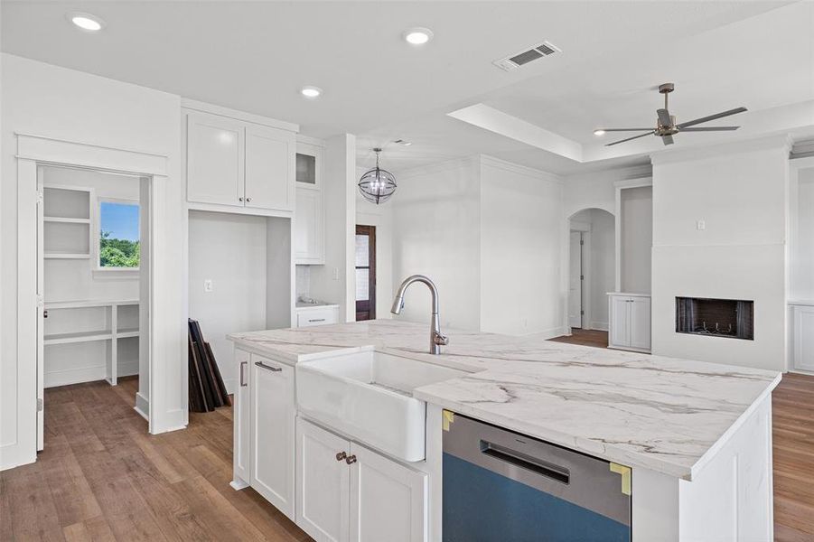 Spacious kitchen featuring a large central island with a farmhouse sink and stainless steel dishwasher