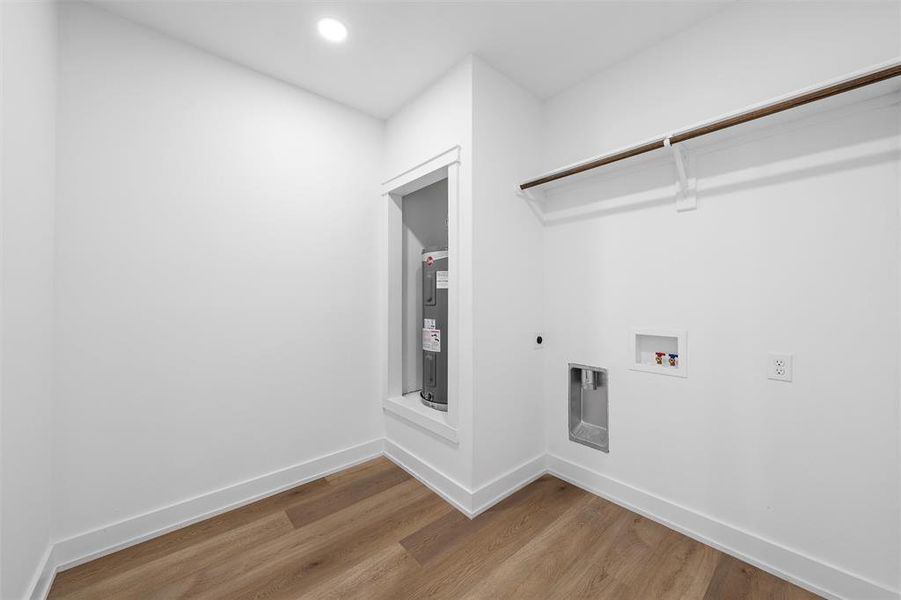 Washroom with light wood-style floors, electric water heater, electric dryer hookup, hookup for a washing machine, and recessed lighting Washroom with light wood-style floors, electric water heater, electric dryer hookup, hookup for a washing machine, and recessed lighting