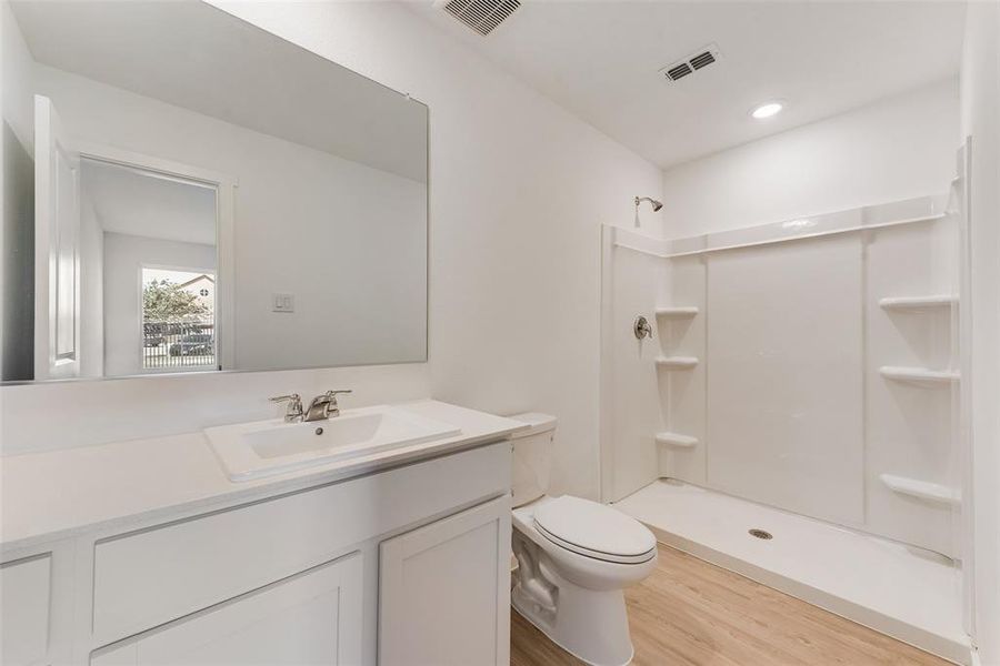 Bathroom featuring walk in shower, vanity, toilet, and hardwood / wood-style floors