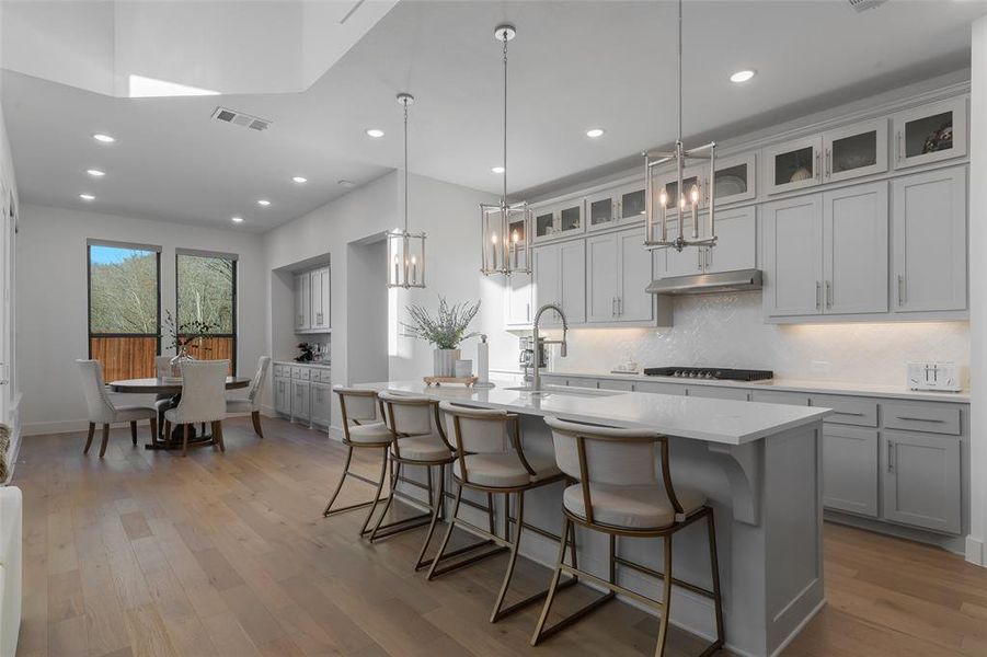 Kitchen featuring under cabinet range hood, gas cooktop, a sink, and wood finished floors