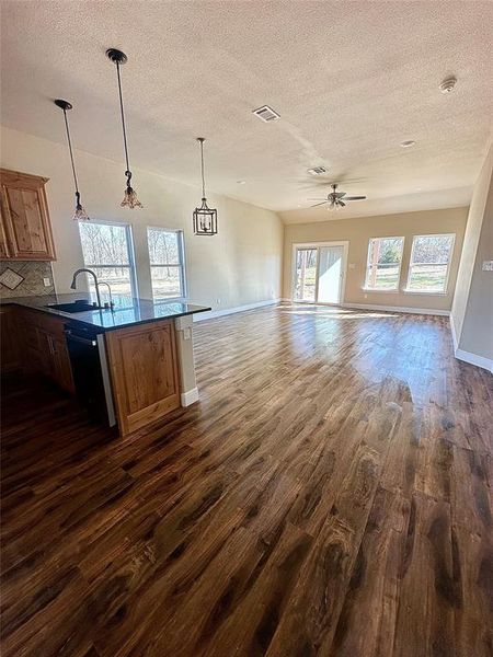 Kitchen with pendant lighting, dishwasher, dark wood-type flooring, decorative backsplash, and sink