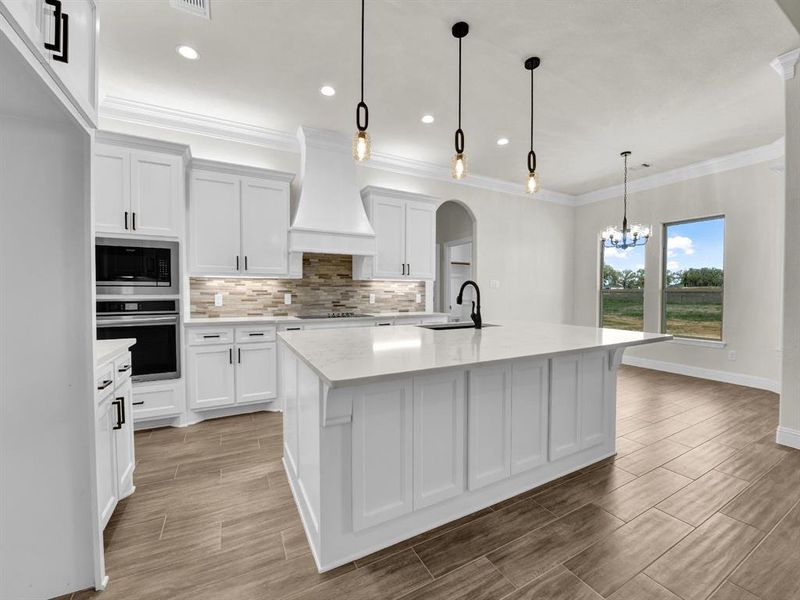 Kitchen with a sink, premium range hood, black electric cooktop, built in microwave, and oven Kitchen with a sink, premium range hood, black electric cooktop, built in microwave, and oven