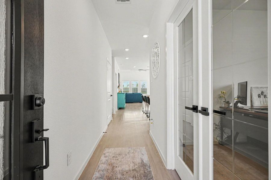 Welcoming entry foyer featuring luxury vinyl plank flooring, modern finishes, and a private study with glass French doors. Welcoming entry foyer featuring luxury vinyl plank flooring, modern finishes, and a private study with glass French doors.