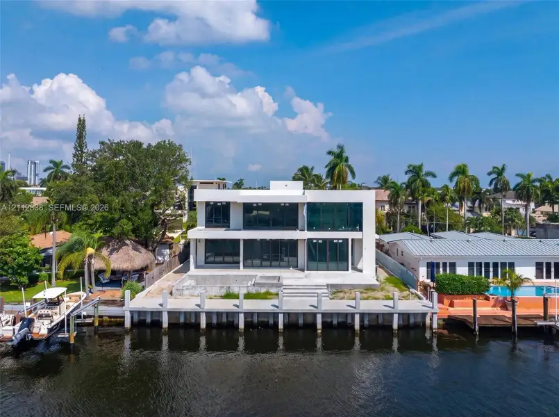 Modern two-story waterfront residence featuring floor-to-ceiling windows, a concrete bulkhead, and a private dock Modern two-story waterfront residence featuring floor-to-ceiling windows, a concrete bulkhead, and a private dock