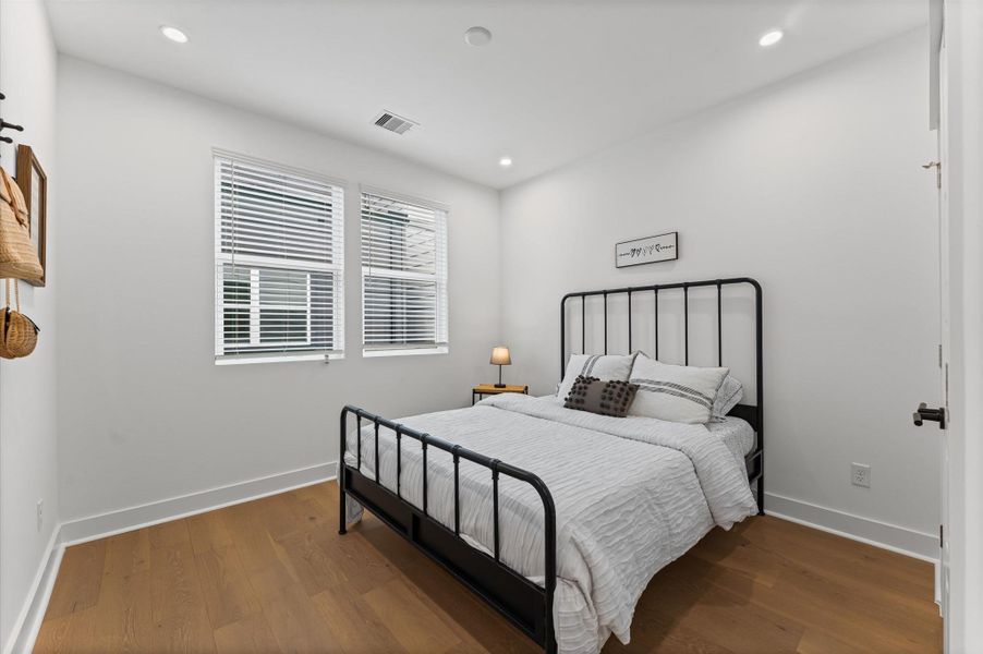 This secondary bedroom on the second floor exudes warmth and sophistication with its rich engineered hardwood flooring, adding a touch of elegance to the space. The smooth, durable surface enhances the room’s clean lines and complements a variety of décor from cozy and traditional to sleek and modern. Natural light dances across the wood grain, creating a serene atmosphere ideal for rest, work, or creative pursuits.