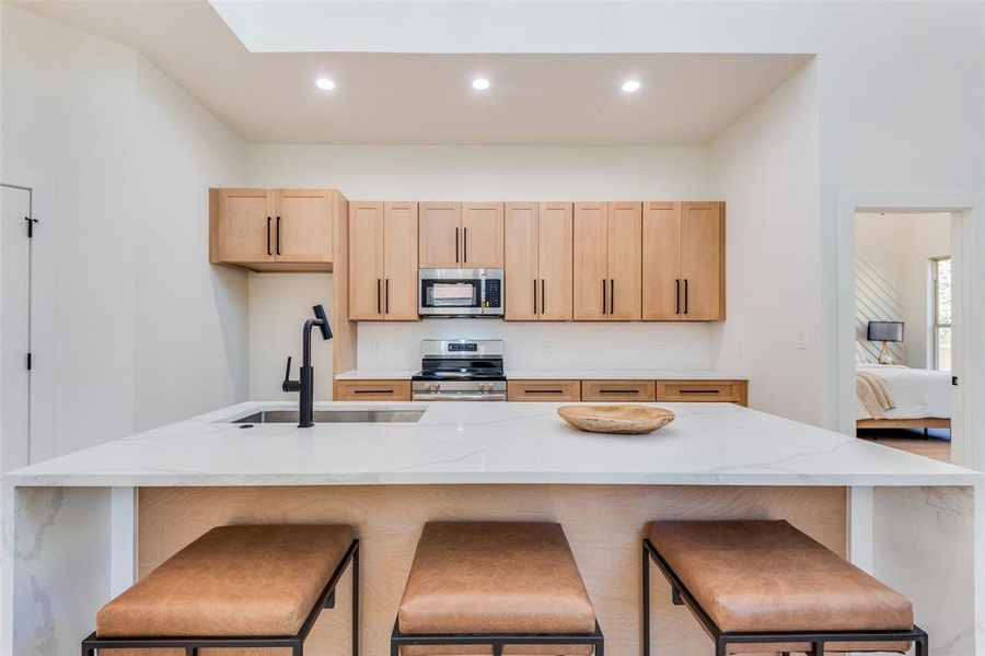 Kitchen featuring light brown cabinets, stainless steel appliances, and a breakfast bar area