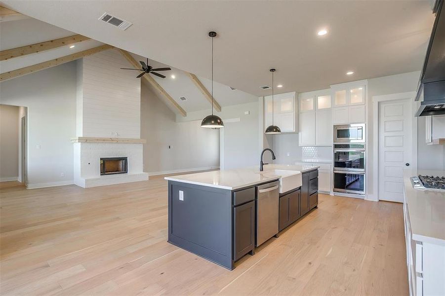 Kitchen with appliances with stainless steel finishes, open floor plan, visible vents, ceiling fan, and a sink