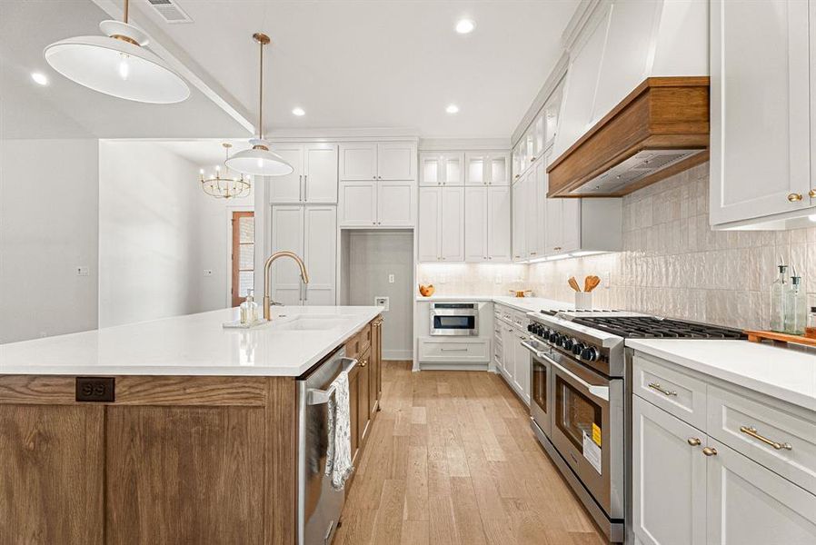 Kitchen with appliances with stainless steel finishes, white cabinets, backsplash, decorative light fixtures, and recessed lighting