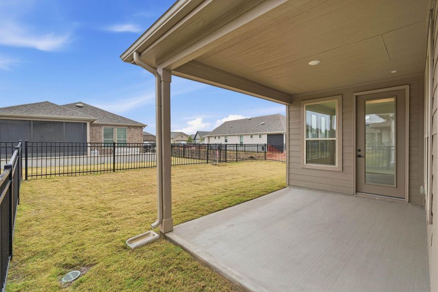 Step out to a covered patio overlooking a fenced backyard, ideal for relaxing, grilling, or enjoying the open lawn beyond.