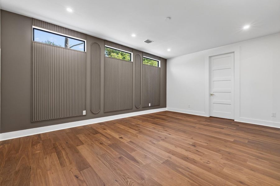 Secondary Primary bedroom offers hardwood flooring, natural light and views of the landscaped property.
