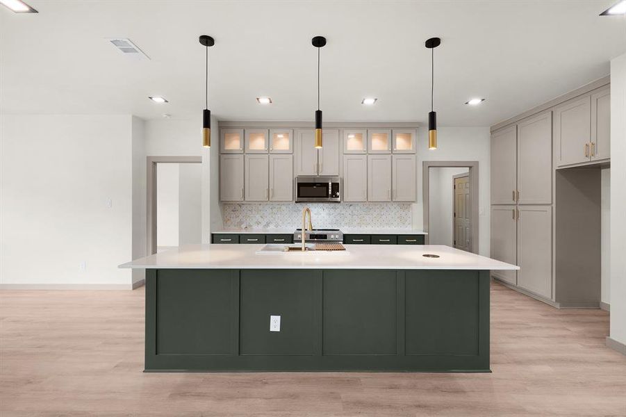 Kitchen featuring light wood-type flooring, baseboards, stainless steel microwave, and tasteful backsplash