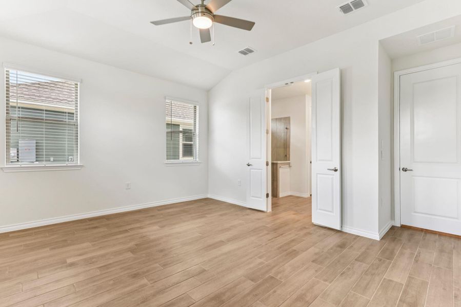 Unfurnished bedroom with light wood-style floors, ceiling fan, and lofted ceiling Unfurnished bedroom with light wood-style floors, ceiling fan, and lofted ceiling