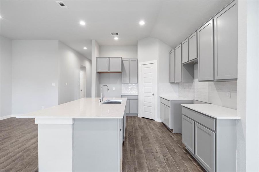 This kitchen is by far any chef’s dream! This spacious kitchen features high ceilings, stained wood cabinets, quartz countertops, large kitchen island with extended counter space for a breakfast bar, SS appliances, modern tile backsplash, recessed lighting, and a walk-in pantry all overlooking your huge family room.