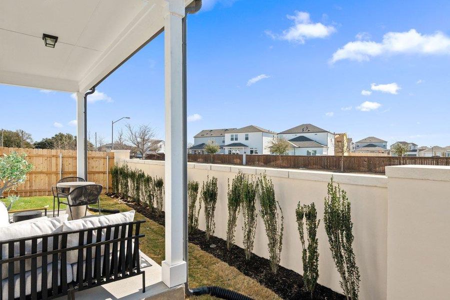 Covered patio featuring a ceiling-mounted light fixture, concrete flooring, and white support columns