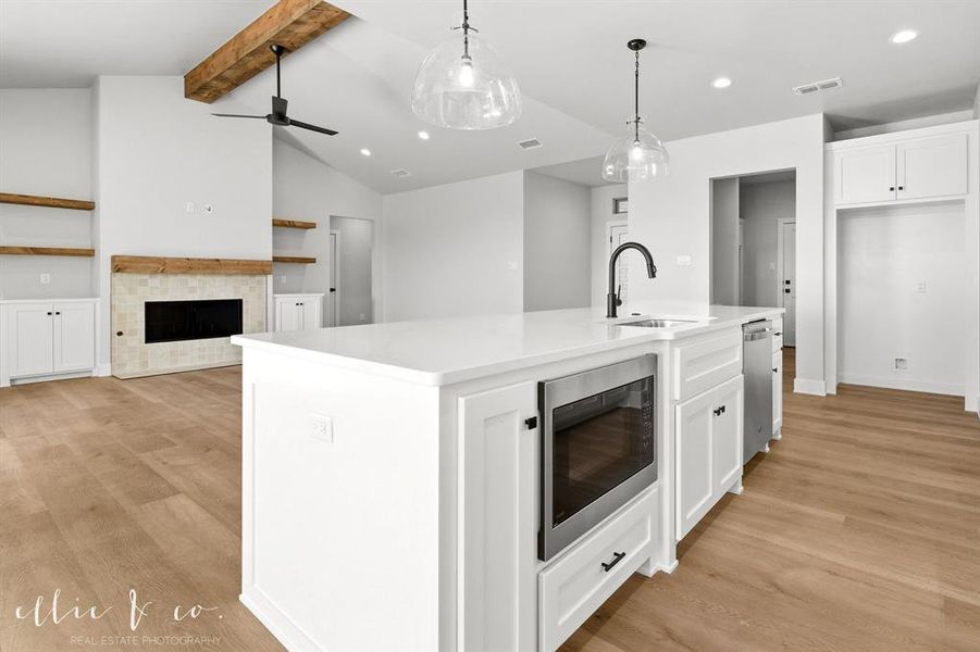 Kitchen with white cabinets, open floor plan, a kitchen island with sink, stainless steel appliances, and light wood-type flooring