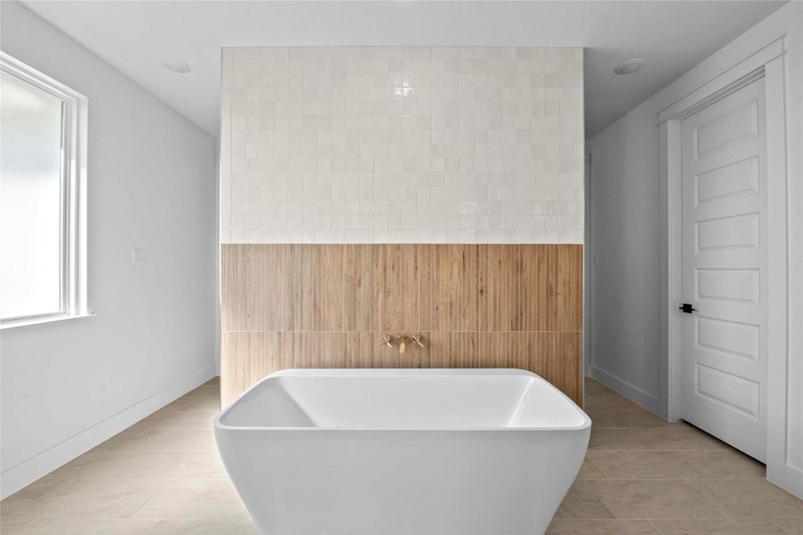 Bathroom featuring a soaking tub, light tile patterned floors, and tile walls Bathroom featuring a soaking tub, light tile patterned floors, and tile walls