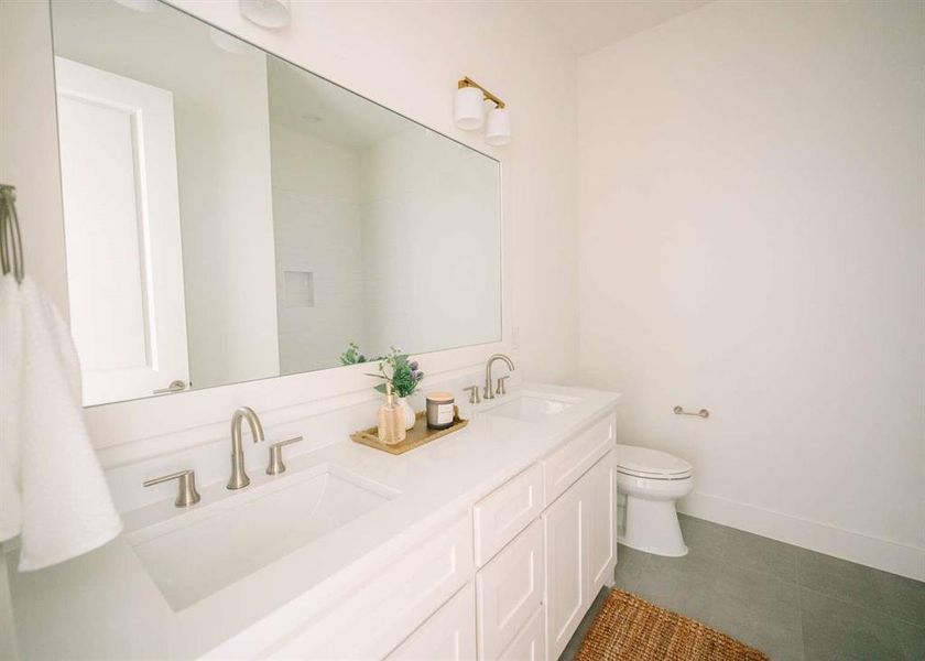 Bathroom featuring dual bowl vanity, tile flooring, and toilet
