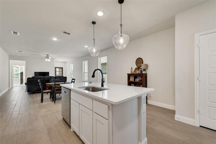 Kitchen with white cabinets, recessed lighting, light wood-style flooring, plenty of natural light, and decorative light fixtures Kitchen with white cabinets, recessed lighting, light wood-style flooring, plenty of natural light, and decorative light fixtures