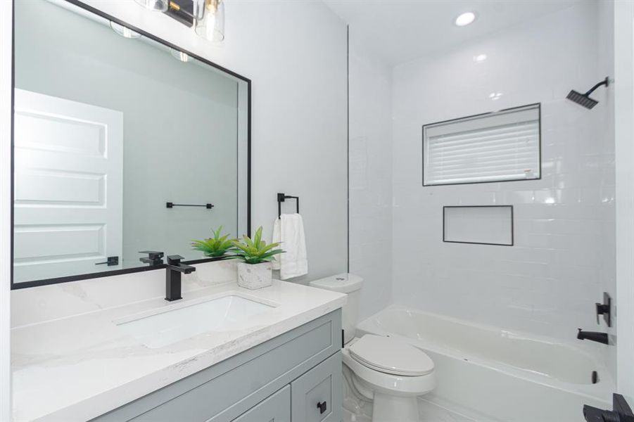 The ensuite full bathroom to the secondary bedroom with quartz countertops and modern fixtures.