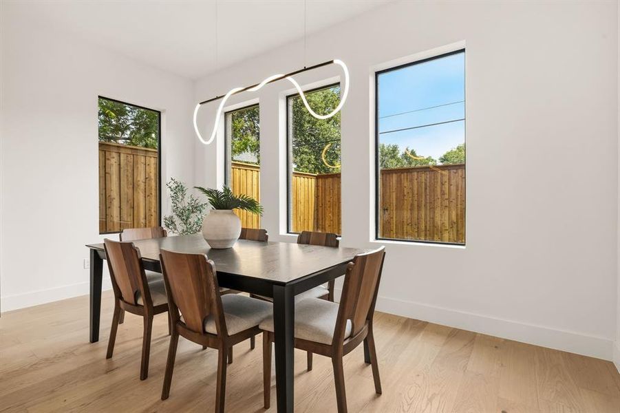 Dining area featuring light wood-finish flooring, white walls, and a contemporary linear pendant light fixture