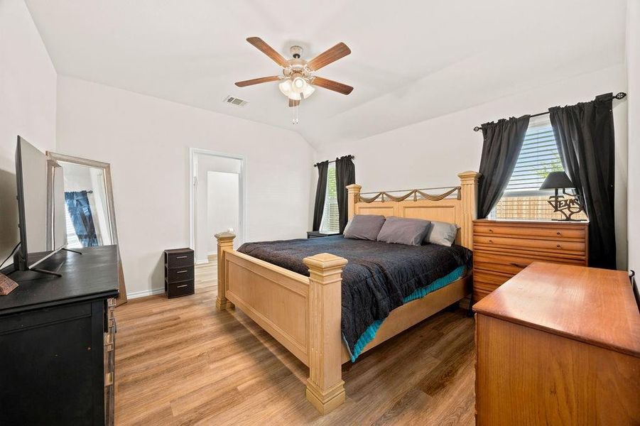 Vaulted ceiling room featuring wood-finish flooring, a ceiling fan with light, and two windows with blinds Vaulted ceiling room featuring wood-finish flooring, a ceiling fan with light, and two windows with blinds