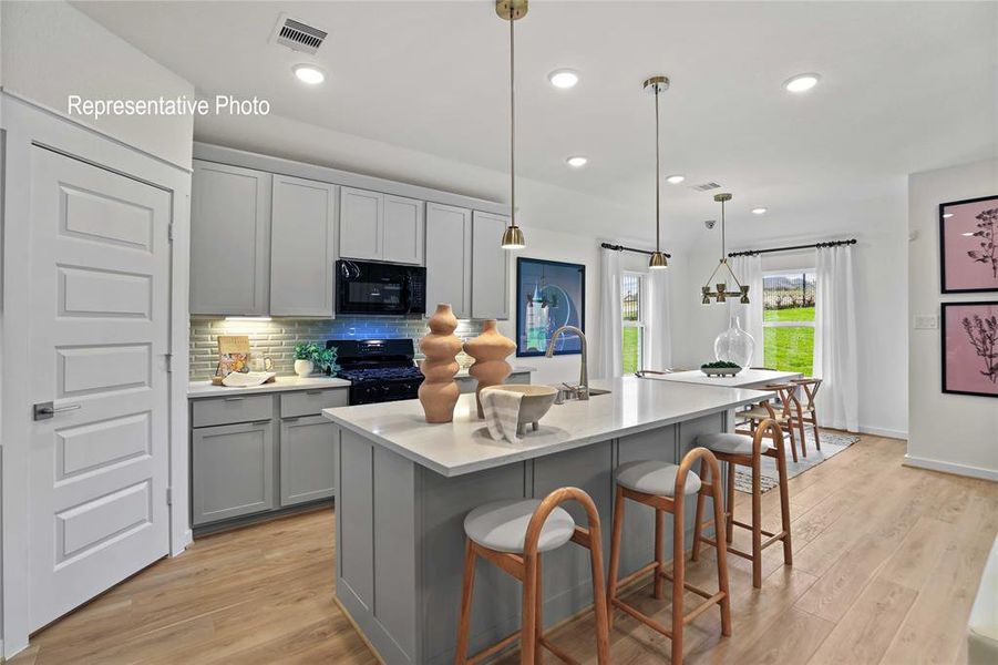 Kitchen island with a light-toned countertop and integrated sink, complemented by light grey cabinetry Kitchen island with a light-toned countertop and integrated sink, complemented by light grey cabinetry