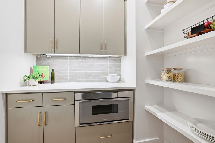 Kitchen featuring gray cabinetry, stainless steel oven, decorative backsplash, and light stone counters