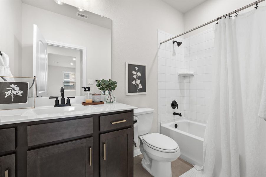 Full bathroom featuring shower / bath combination, vanity, and dark tile patterned floors Full bathroom featuring shower / bath combination, vanity, and dark tile patterned floors