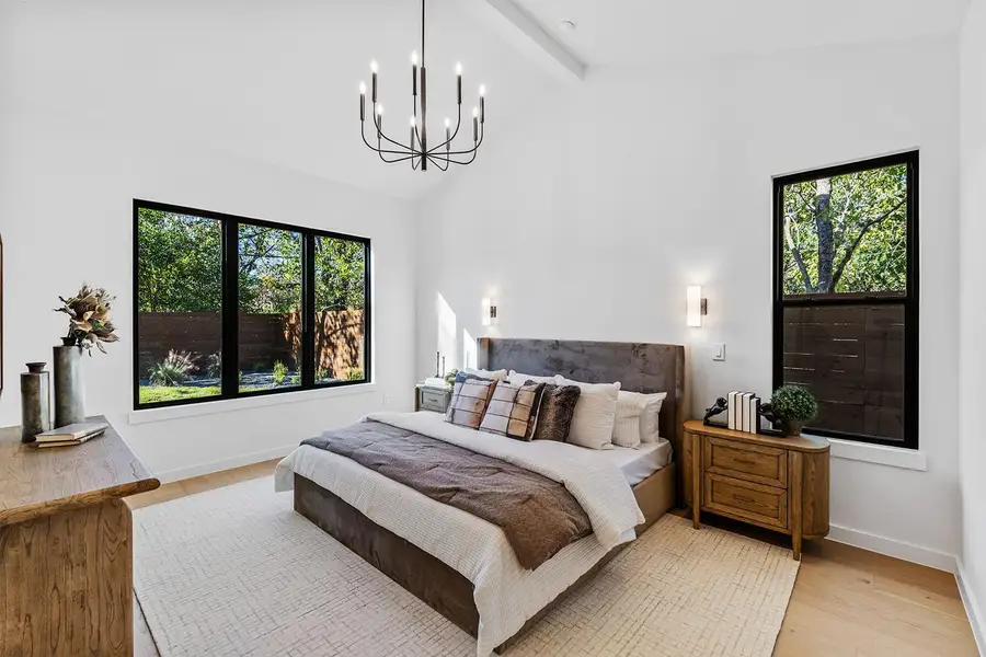 Bedroom with wood finished floors, beam ceiling, a chandelier, and high vaulted ceiling