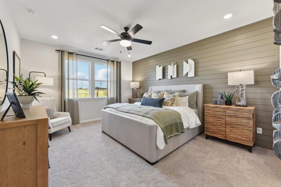 Plush carpeting and custom wall paneling create a comfortable atmosphere in this inviting bedroom.