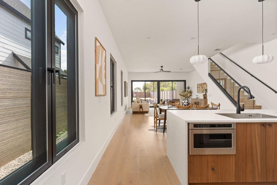 Natural light floods this open-concept interior featuring hardwood flooring and a stylish kitchen island with integrated appliances.
