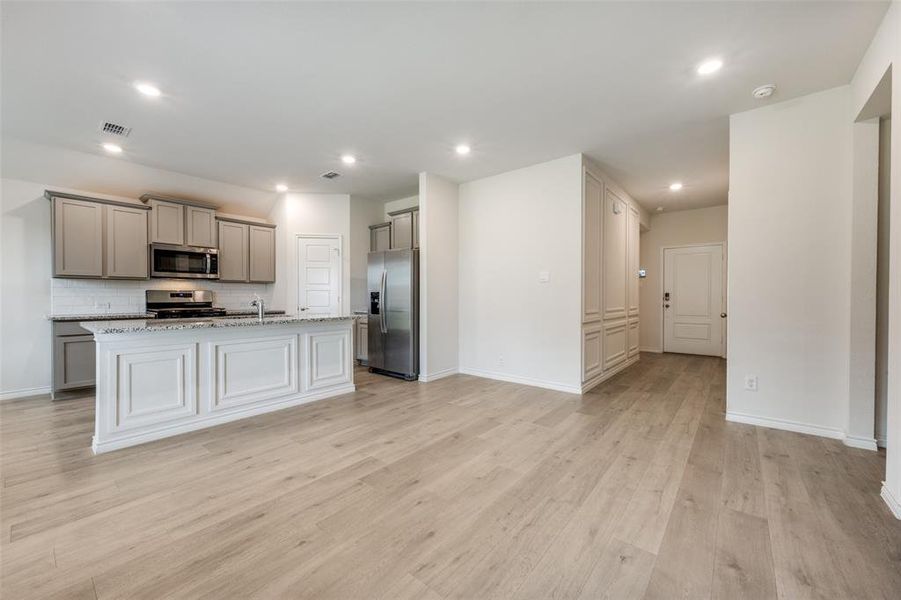 Kitchen with gray cabinetry, decorative backsplash, appliances with stainless steel finishes, light wood-style floors, and recessed lighting