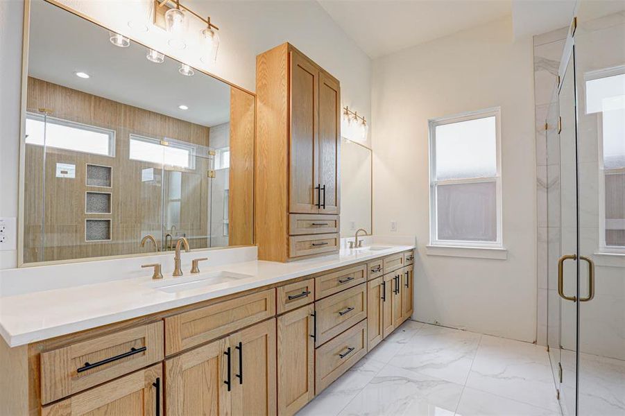 Bathroom with double vanity, a shower stall, and marble look tiles