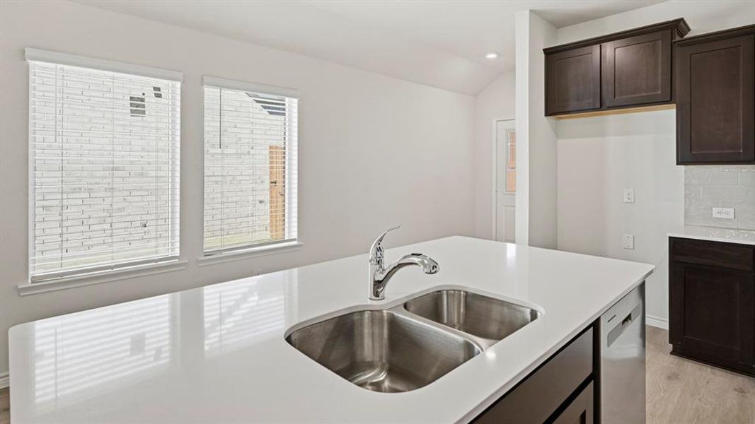 Kitchen with dark brown cabinetry, recessed lighting, light wood-type flooring, dishwasher, and lofted ceiling