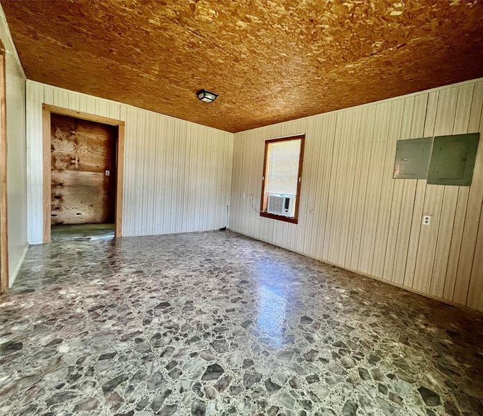 Unfurnished Primary bedroom with electric panel, stone laminated floors, and wood walls Unfurnished Primary bedroom with electric panel, stone laminated floors, and wood walls