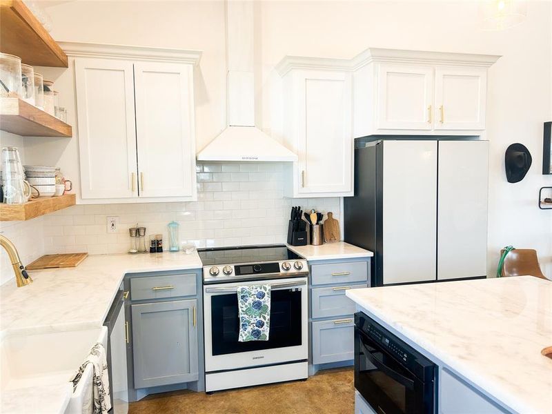 Kitchen with open shelves, stainless steel appliances, white cabinetry, and decorative backsplash Kitchen with open shelves, stainless steel appliances, white cabinetry, and decorative backsplash