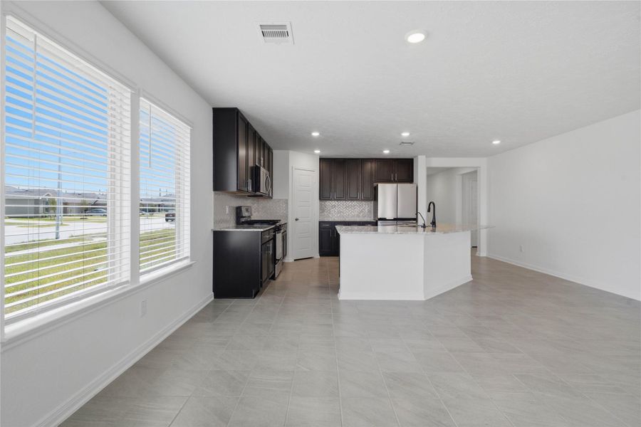 Start your day with a warm cup of coffee and quality time in this charming dining area! Highlights include large windows with blinds, custom neutral paint, durable tile flooring, recessed lighting, and high ceilings.