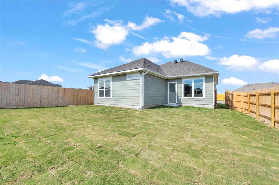 Back of house with a fenced backyard and a shingled roof