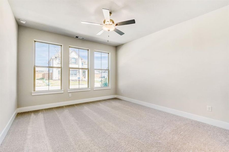 Spare room featuring light colored carpet and a ceiling fan