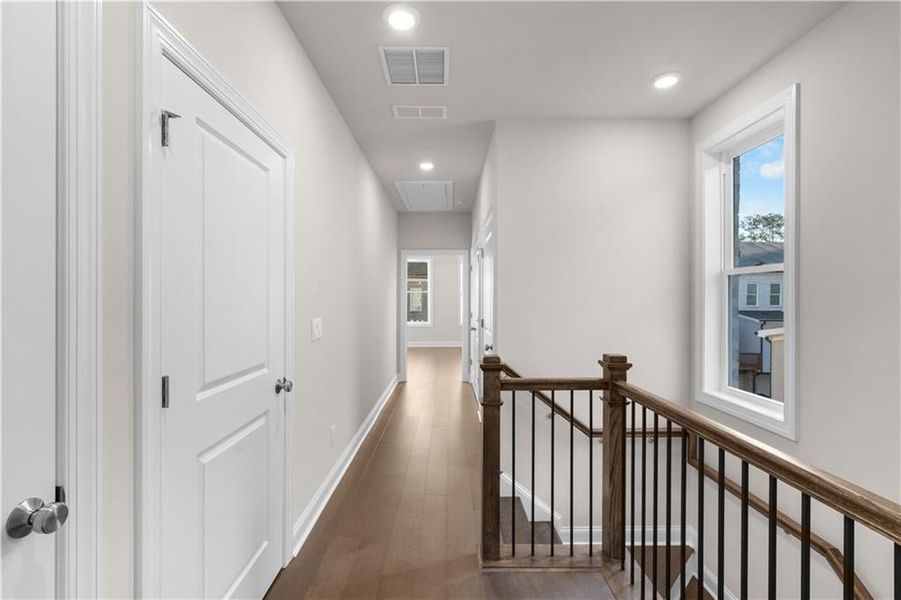 Hall with an upstairs landing, recessed lighting, dark wood-style flooring, and attic access